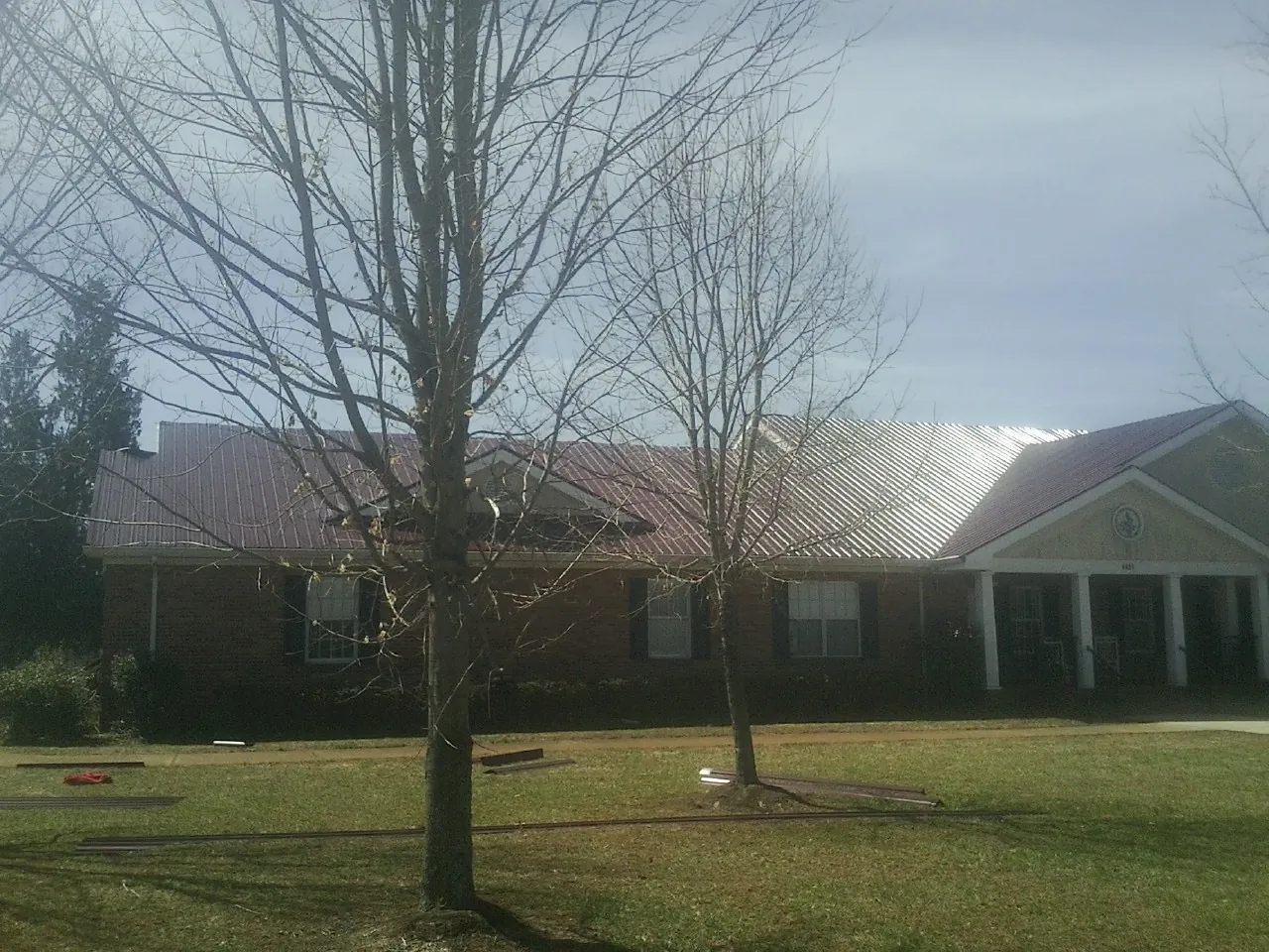 Red metal roof on a brick building seen from the front lawn in Ringwood