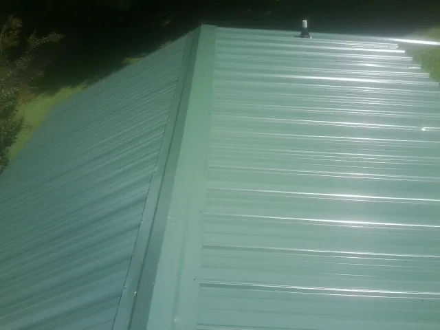 New green metal panels meeting at the ridge of a roof — Flat Roof Repair work by our crew in Ringwood