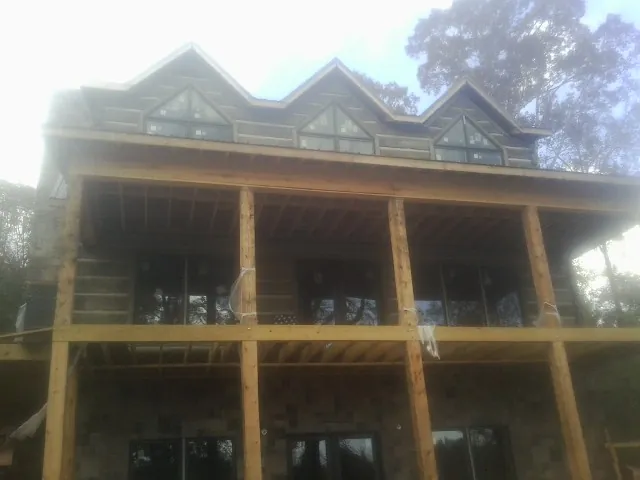 Dormers and porch framing on a large log home under construction — Roof Coating work by our crew in Ringwood