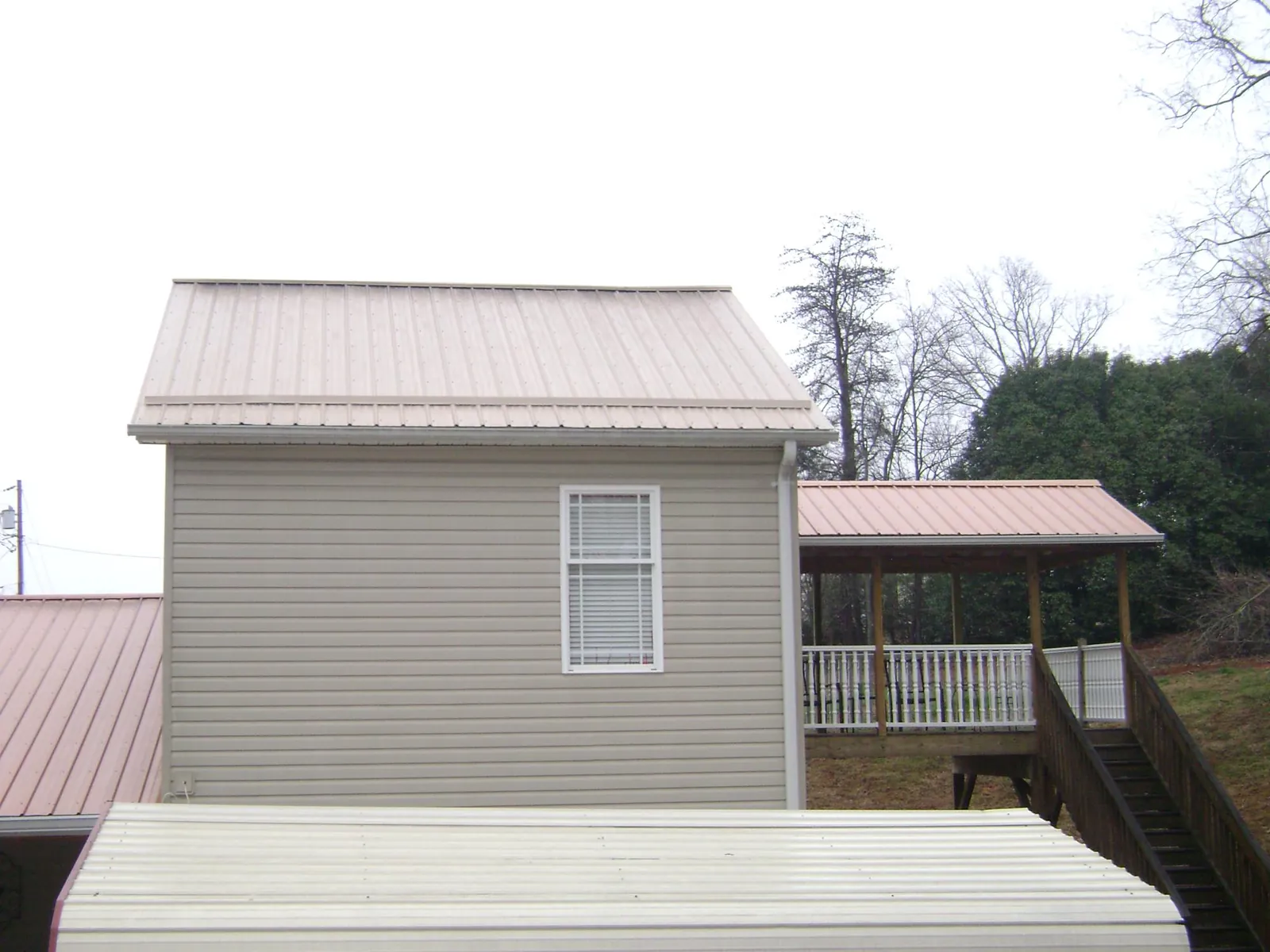 Tan metal roofs on a two story addition and attached porch, from a Roof Replacement job in Ringwood